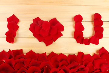 Words I Love You formed from roses petals on wooden background