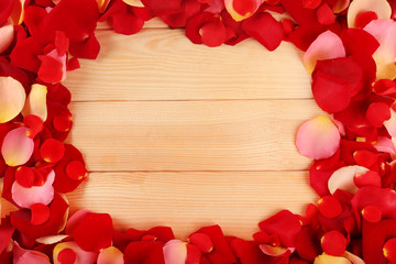 Frame of rose petals on wooden background