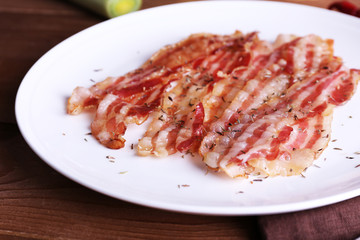 Strips of bacon in white plate with spices and chili pepper