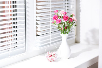 Bouquet of pink roses in white vase on windowsill background
