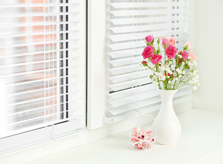 Bouquet of pink roses in white vase on windowsill background