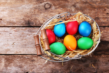 Easter eggs in basket on vintage wooden planks background