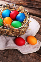 Easter eggs in basket on vintage wooden planks background