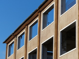 Fassade eines Abbruchhaus mit leeren Fenstern vor blauem Himmel im Sonnenschein auf einer Baustelle...