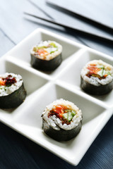 Vegetable sushi rolls on plate on color wooden background