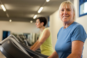 Smiling mature woman is looking towards the camera while running