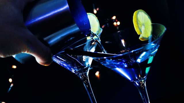 barman pouring blue cocktail drink on a disco bar table