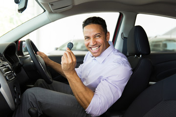 middle aged man showing a car key inside his new vehicle