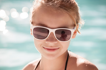 Little blond girl in sunglasses, close-up portrait