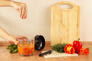 Hands of chef salt cooked vegetable mix in a blender