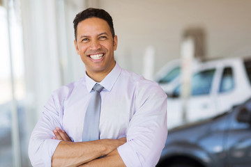 vehicle dealership principal with arms crossed in showroom
