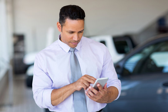 Mid Age Car Salesman Using Cell Phone