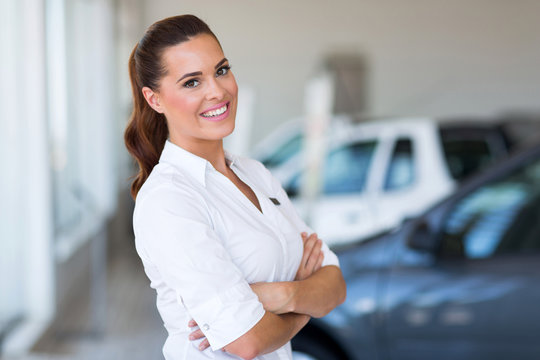 vehicle saleswoman with arms folded in showroom