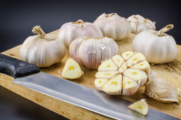 Bulbs of fresh garlic with several cloves on the cutting board.