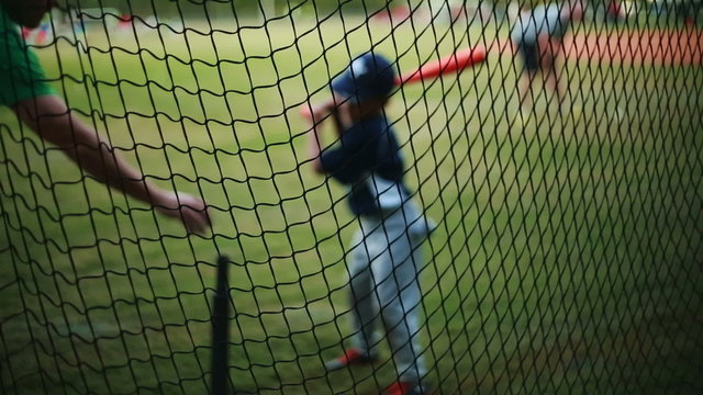 Shot from behind net of a Kid Practicing his Batting