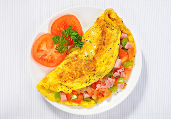 Delicious omelet with tomato, pepper, ham, basil