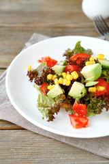 Summer salad with avocado, tomatoes and corn on a white plate