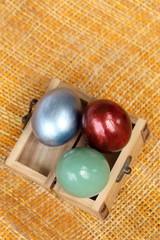 Colorful easter eggs in small wood case on bamboo weave sheet ba