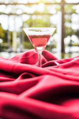 Wine glass with red wine on a red cloth.