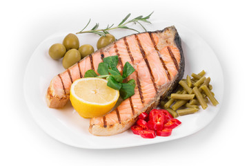 Grilled salmon steak with vegetables on plate.