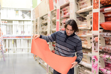 man holding a roll of wallpaper in the store