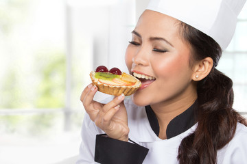 young female chef eat cake