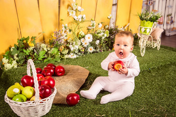 little girl sitting on the grass and holding apple 