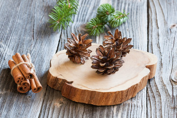 Cinnamon and pine cones on wood background
