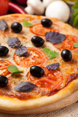 Pizza margherita with tomatoes, olive oil and basil close up on