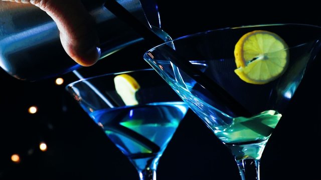 barman pouring blue and yellow cocktail drink on disco bar table