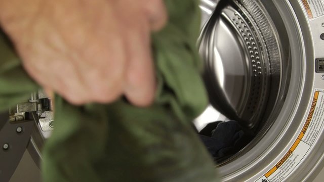 Man putting dirty clothes in washing machine - Lifestyle concept