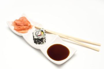 maki sushi  with pickled ginger and soy sauce on white ceramic plate and chopsticks on white background