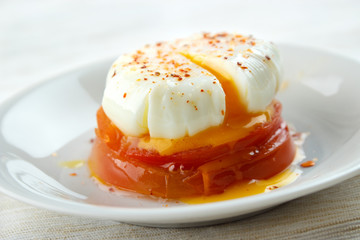 Poached egg above cooked tomato slices on dish