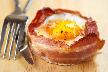 Oven cooked bacon wrapped egg with utensils