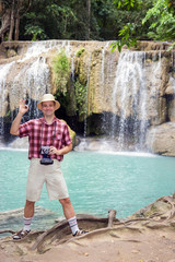 tourist posing beside waterfall