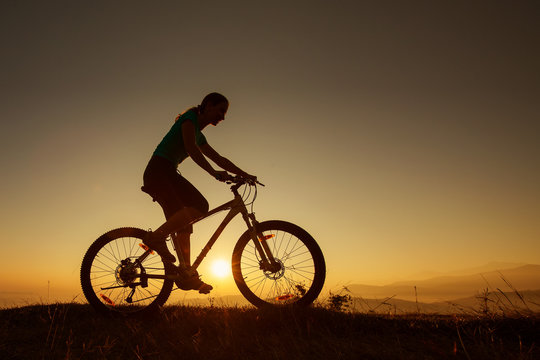 Biker-girl at the sunset on mountains