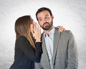 young girl whispering to her boyfriend over white background