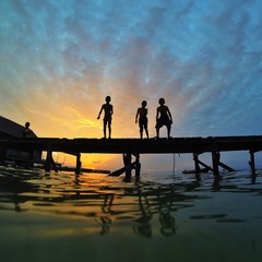 silhouette of young boys at bridge during sunset