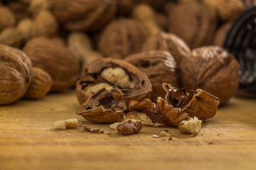 Geknackte Walnuss vor einer Nussmischung auf einer Holzplatte