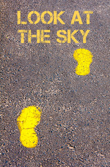Yellow footsteps on sidewalk towards Look at the sky message