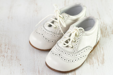 white baby shoes on white wooden background