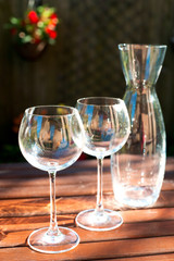 Two transparent shiny empty wineglasses and carafe in rays of su