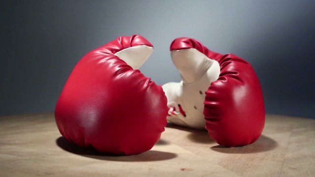 Red boxing gloves rotate on wooden table