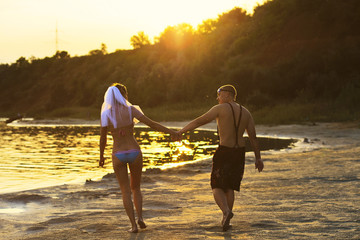 man and woman are on the beach and holding hands