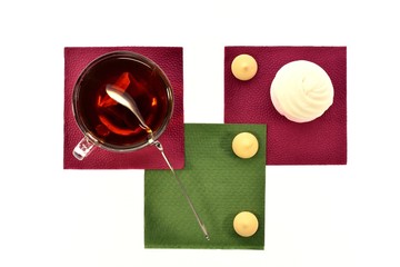 Cup of black tea with a spoonful marshmallows and on napkins