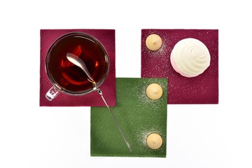 Cup of black tea with a spoonful marshmallows on napkins