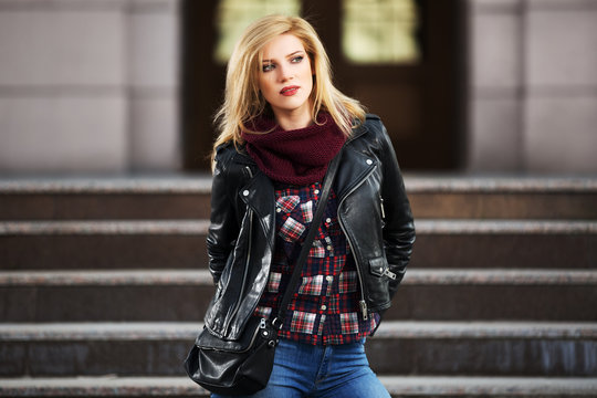Young fashion blond woman in leather jacket on the steps