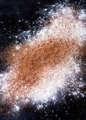 Dusted wheat flour and cocoa powder on dark background