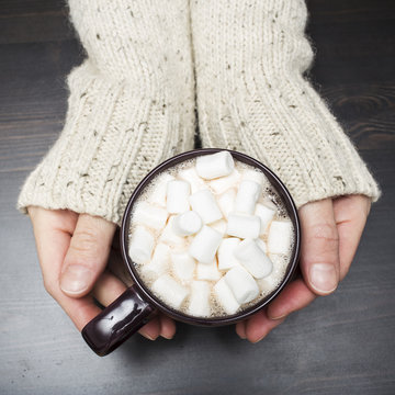 warming cup of cocoa with marshmallows in the hands