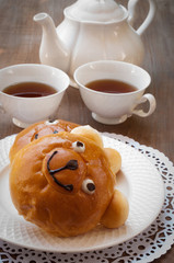 Sweet bun and cup of tea on wooden table
